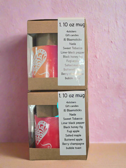 Two stacked cardboard boxes with clear windows containing a pink candle and labels on a textured wall background.